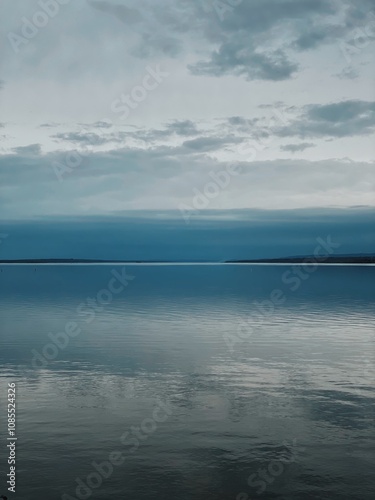 Peaceful view of the Ottawa River on a serene autumn day, with soft shades of blue and gray blending the calm water and cloudy sky, creating a tranquil and reflective atmosphere