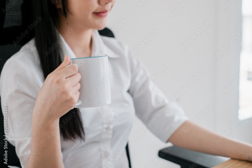 Businesswoman Enjoying a Coffee Break at Her Desk in a Modern Office Setting Businesswoman Enjoying a Coffee Break at Her Desk in a Modern Office Setting