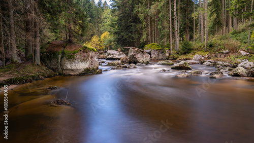 ursprüngliche Flusslandschaft mitten in einem Nadelwald, Langzeitbelichtung zeigt Bewegung des Wassers, Felsbrocken liegen im Fluss
 photo