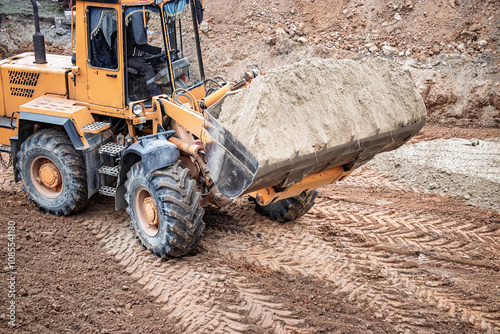 Heavy machinery moves sand at a construction site in the early morning light, preparing for a new building project in the city