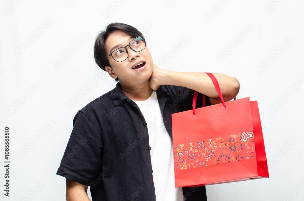 Attractive and stylish young Asian man holding red batik-patterned shopping bags. Attractive and stylish young Asian man holding red batik-patterned shopping bags.