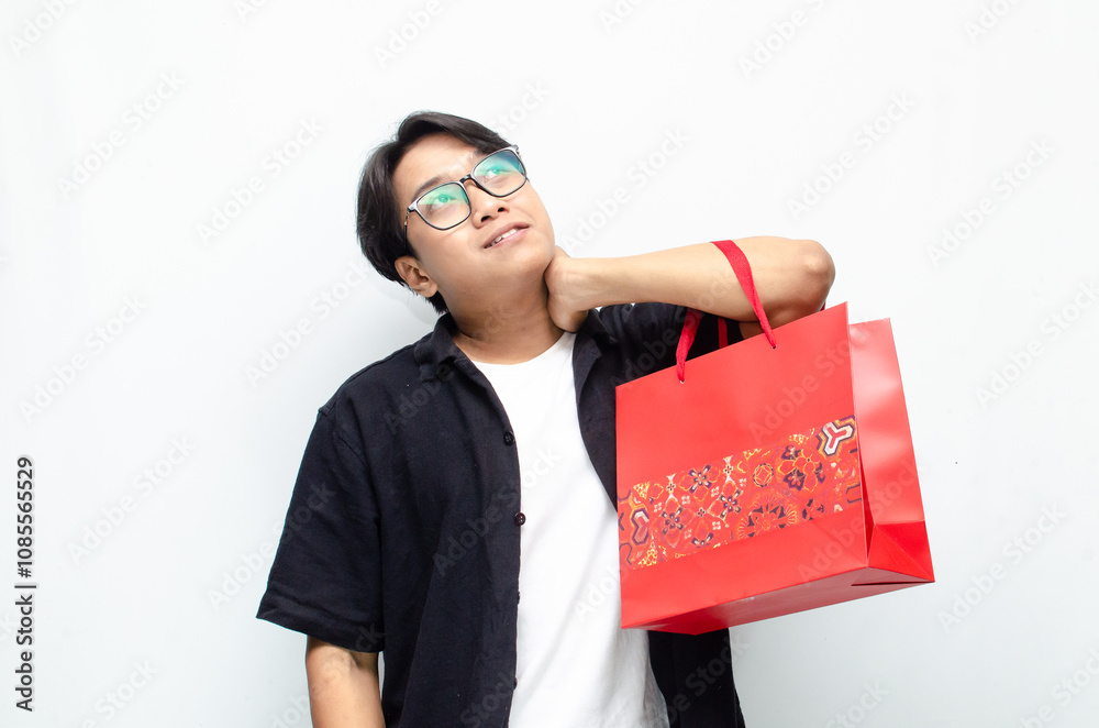 Attractive and stylish young Asian man holding red batik-patterned shopping bags. Attractive and stylish young Asian man holding red batik-patterned shopping bags.