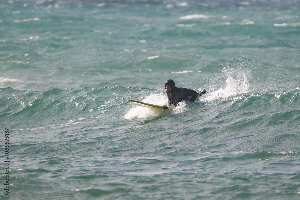 surfer in a wetsuit on a board glides through the waves in a strong wind