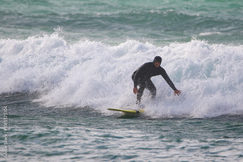 Obraz na płótnie surfer in a wetsuit on a board glides through the waves in a strong wind w salonie
