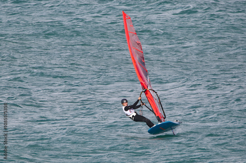 windsurfer in a wetsuit on a board glides through the waves in a strong wind