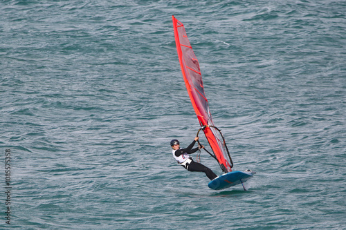 Obraz na płótnie windsurfer in a wetsuit on a board glides through the waves in a strong wind w salonie
