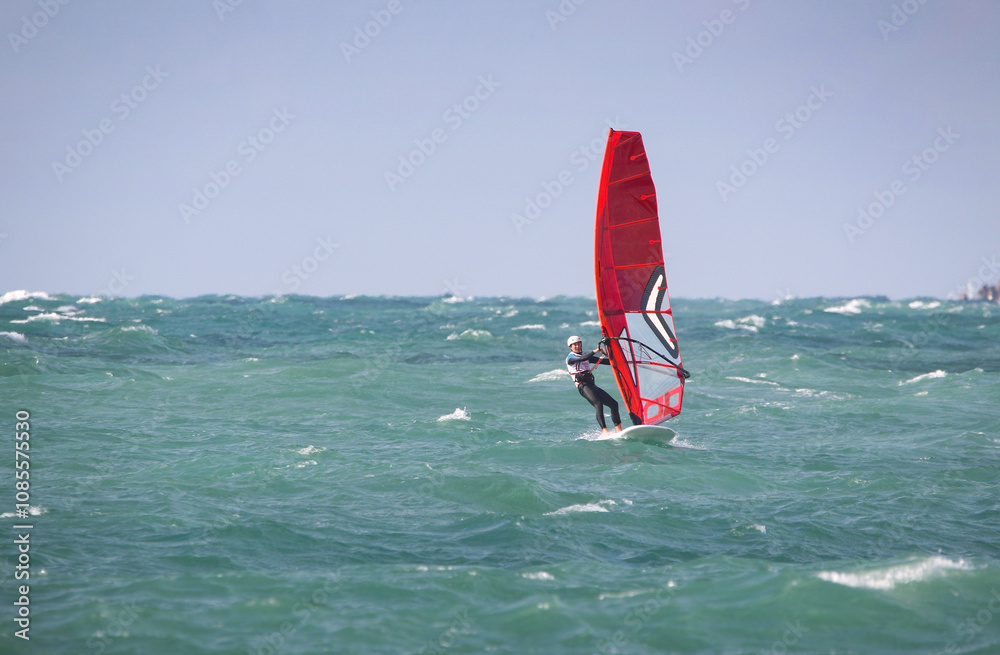 windsurfer in a wetsuit on a board glides through the waves in a strong wind