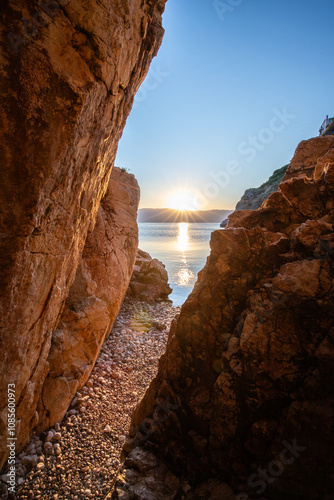 Fototapeta Naklejka Na Ścianę i Meble -  Hidden cove and beach with an old hilltop village. The sunrise is reflected in the water. A beautiful landscape shot framed by cliffs and the Adriatic sea from Vrbnik, Krk, Croatia