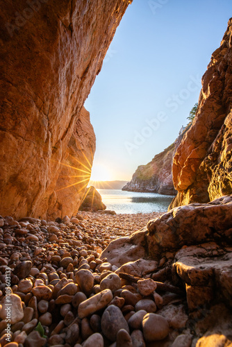 Fototapeta Naklejka Na Ścianę i Meble -  Hidden cove and beach with an old hilltop village. The sunrise is reflected in the water. A beautiful landscape shot framed by cliffs and the Adriatic sea from Vrbnik, Krk, Croatia