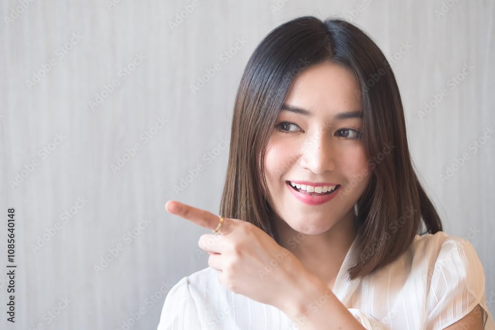 Young adult Asian woman pointing finger up to her side Young adult Asian woman pointing finger up to her side