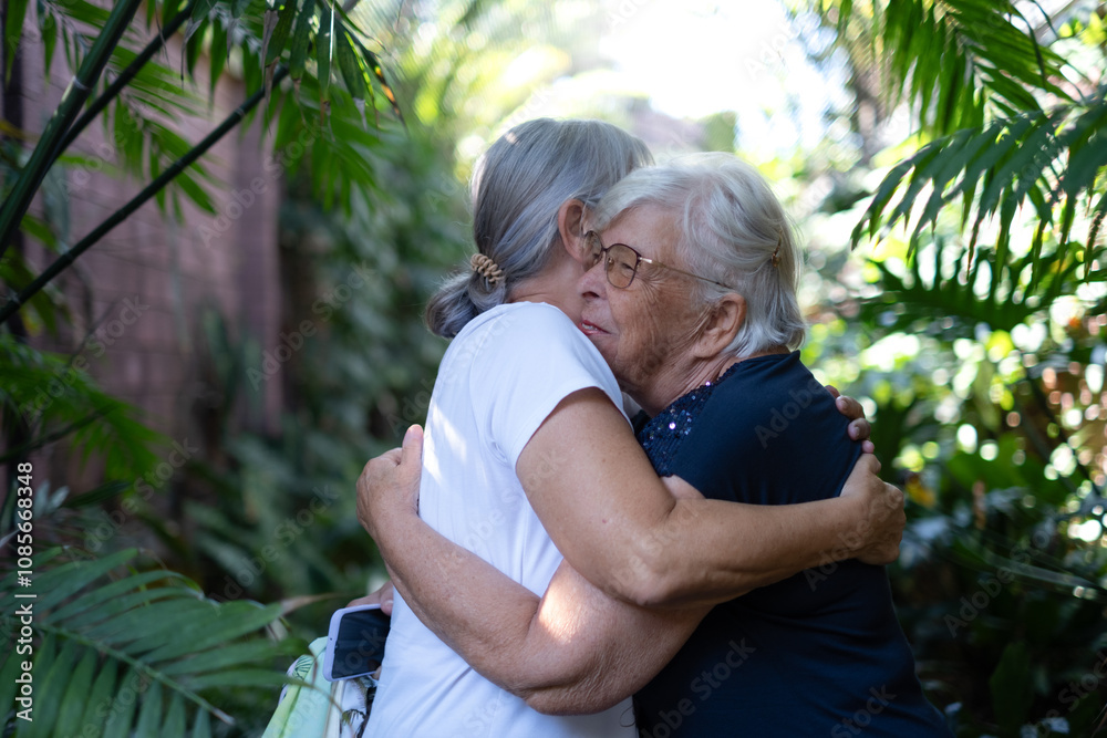 Fototapeta premium Senior old couple of women in friendship embrace with affection in the park in a sunny day expressing love and care