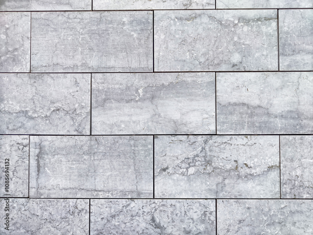Fototapeta premium Textured gray stone wall featuring rectangular tiles arranged in a neat pattern, suitable for modern interiors or exteriors