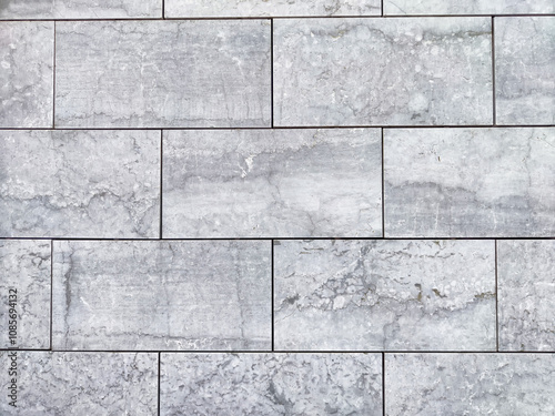 Textured gray stone wall featuring rectangular tiles arranged in a neat pattern, suitable for modern interiors or exteriors