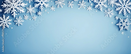 Snowflakes of different sizes and shapes creating a winter frame on a light blue background with a brighter central area. Christmas template.