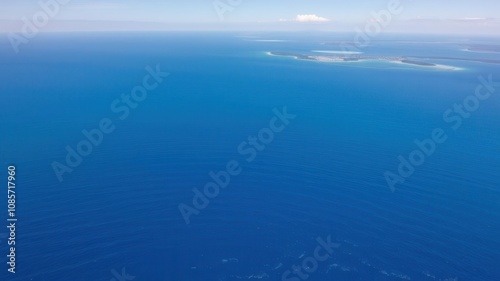 A breathtaking aerial view of a vast and peaceful ocean with crystal clear blue waters, gentle waves, and islands in the distance, waves, beauty, aerial