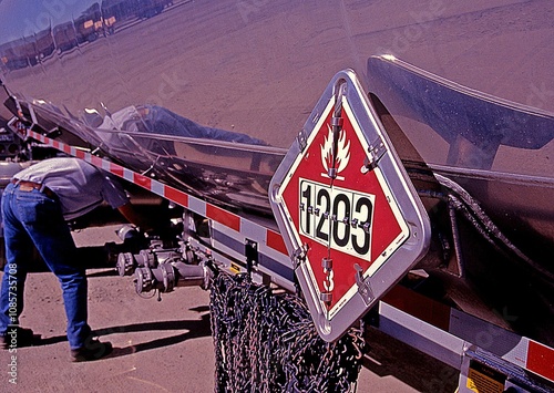 Flammables placard on fuel tank trailer with driver
in background.