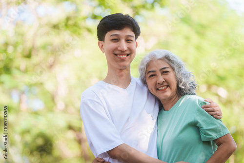 Young son and his mature mom asian people share loving hug in beautiful park, surrounded by nature. Their happiness radiates as they bond outdoors, celebrating family love and togetherness.