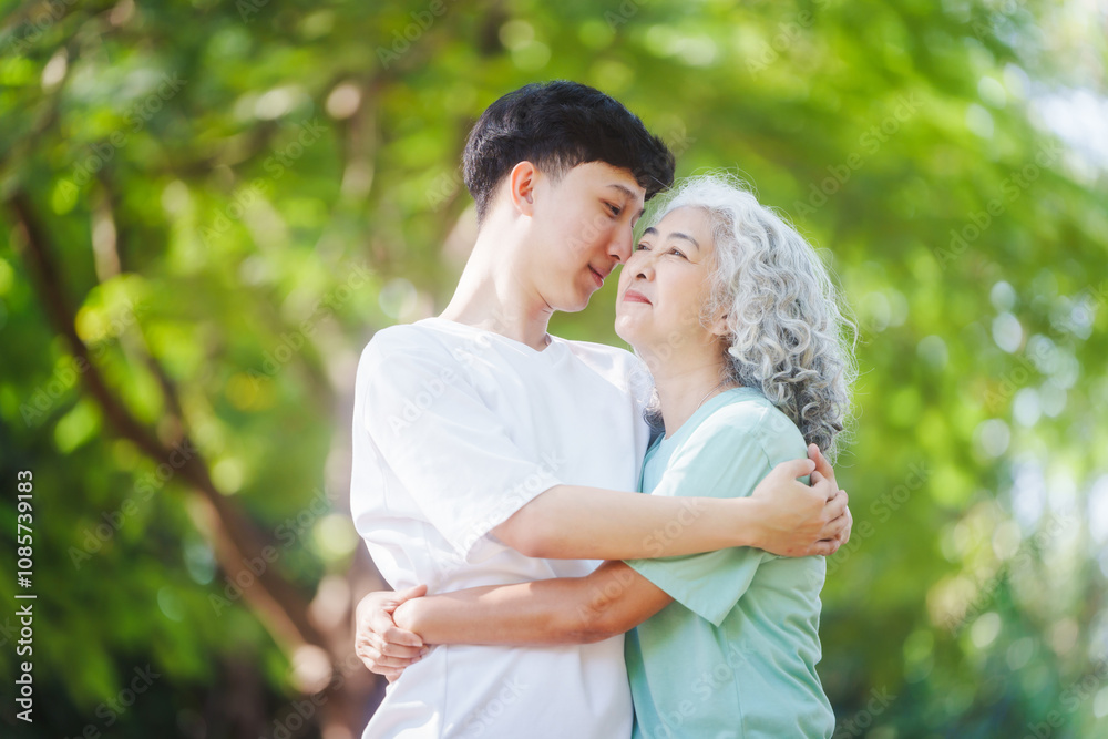 Young son and his mature mom asian people share loving hug in beautiful park, surrounded by nature. Their happiness radiates as they bond outdoors, celebrating family love and togetherness. Young son and his mature mom asian people share loving hug in beautiful park, surrounded by nature. Their happiness radiates as they bond outdoors, celebrating family love and togetherness.