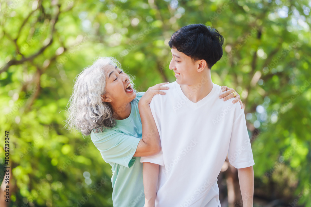 Young son and his mature mom asian people share loving hug in beautiful park, surrounded by nature. Their happiness radiates as they bond outdoors, celebrating family love and togetherness. Young son and his mature mom asian people share loving hug in beautiful park, surrounded by nature. Their happiness radiates as they bond outdoors, celebrating family love and togetherness.