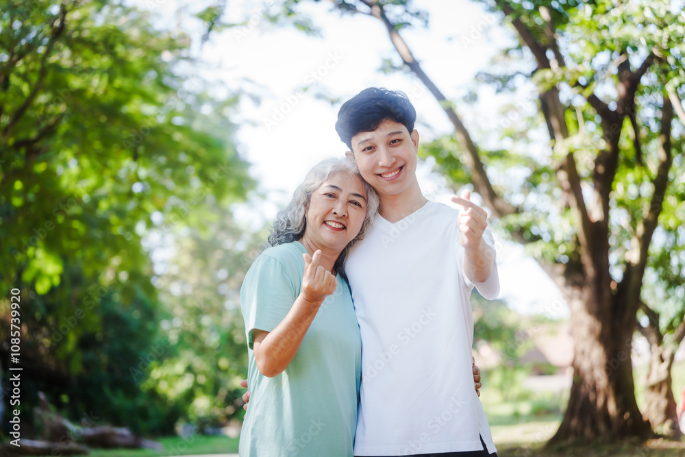 Young son and his mature mom asian people share loving hug in beautiful park, surrounded by nature. Their happiness radiates as they bond outdoors, celebrating family love and togetherness. Young son and his mature mom asian people share loving hug in beautiful park, surrounded by nature. Their happiness radiates as they bond outdoors, celebrating family love and togetherness.
