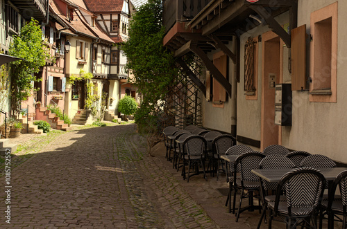 Charming cityscape view of narrow medieval cobblestone street between colorful stone houses in Eguisheim. Traditional architecture in Alsace in northeastern France. Travel and tourism concept