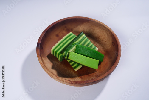 Sticky layer cake or Kue Lapis on wooden plate isolated on white background. Indonesian traditional dessert made from rice flour and coconut milk, steamed layer by layer served on banana leaves. Selec photo