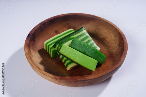 Sticky layer cake or Kue Lapis on wooden plate isolated on white background. Indonesian traditional dessert made from rice flour and coconut milk, steamed layer by layer served on banana leaves. Selec photo