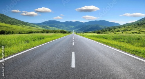 wide road leads into the distance, with green mountains and a blue sky in the background