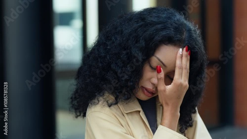 Frustrated young woman with her hand on her forehead, expressing stress or concern in an urban environment.