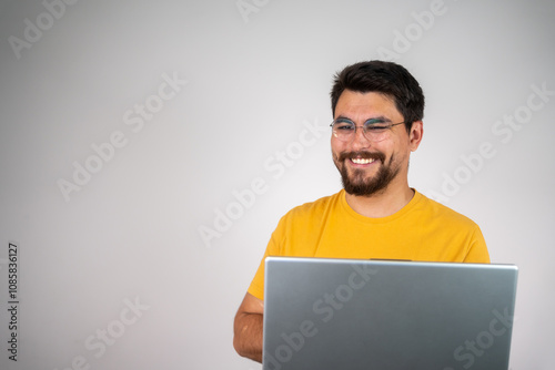 Happy freelancer working on a laptop against an isolated background, focused on his tasks, showcasing a productive and positive work-from-home environment.