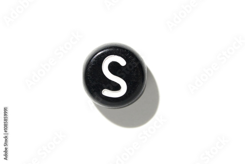 Black round salt shaker with white letter s casting shadow on a white background in minimalist style photo