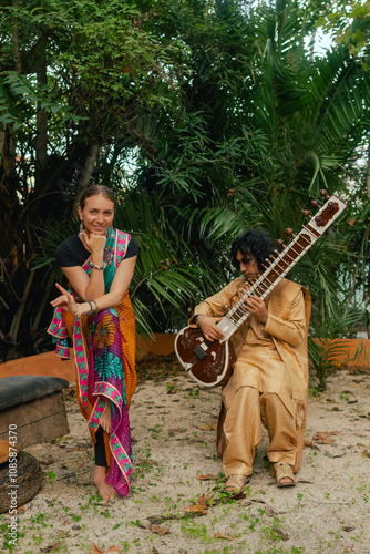 Indian musician in traditional clothes playing sitar festive season outdoor home. Smiling young woman in traditional saree dancing and enjoy festival. Happy Diwali greeting photo. Part of a series photo