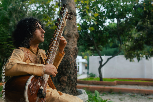 Fotografie Indian musician in traditional clothes playing sitar festive season outdoor home