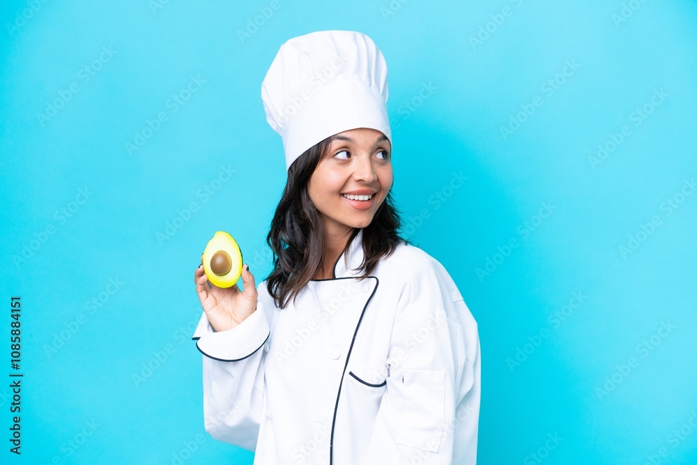 Young hispanic chef woman holding avocado isolated on blue background thinking an idea while looking up Young hispanic chef woman holding avocado isolated on blue background thinking an idea while looking up