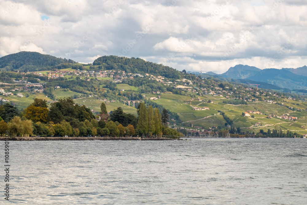 Lake Geneva with autumn trees at the Lausanne lakefront and, behind, the hills of Pully, Switzerland Lake Geneva with autumn trees at the Lausanne lakefront and, behind, the hills of Pully, Switzerland