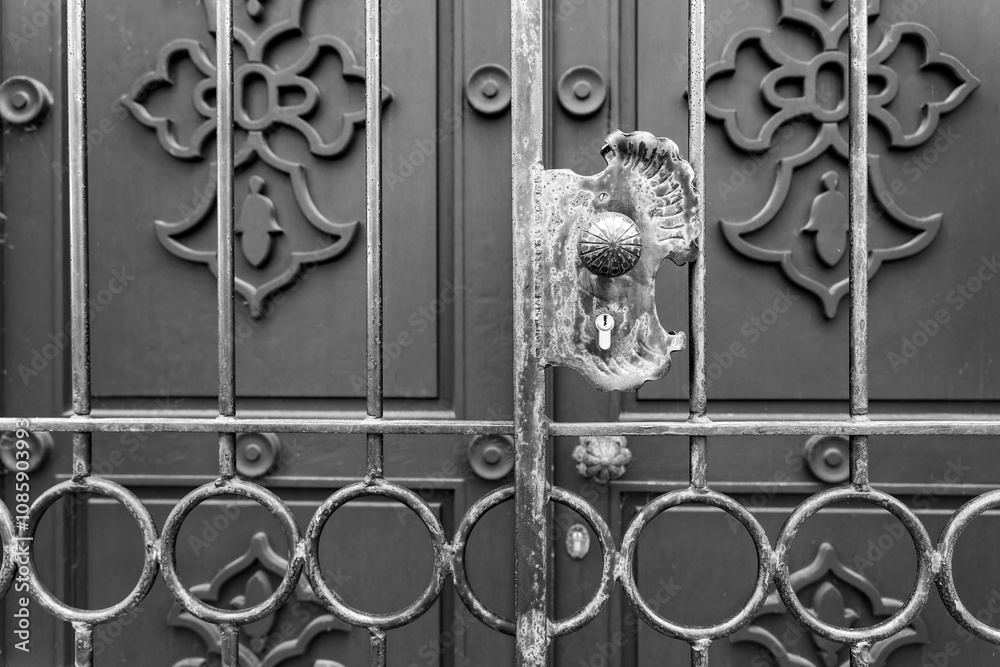 Close-up view of a heavily worn, ornate metal door handle and gate Close-up view of a heavily worn, ornate metal door handle and gate