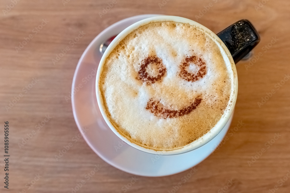 A white cup of cappuccino rests on a saucer atop a light brown wooden table A white cup of cappuccino rests on a saucer atop a light brown wooden table