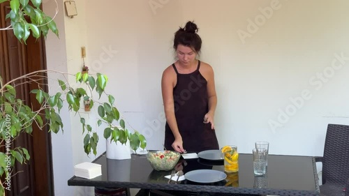Woman cutting orange for lemonade, preparing healthy salad and serving table 