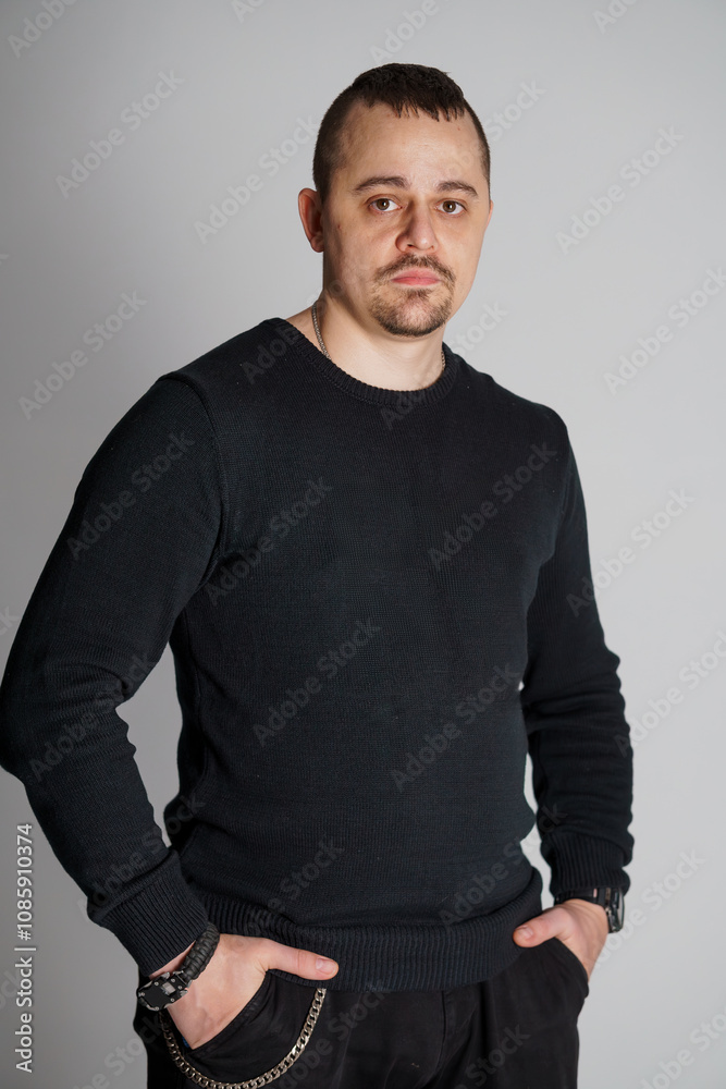 A Confident Man in a Black Sweater Posing Against a Plain Background A Confident Man in a Black Sweater Posing Against a Plain Background
