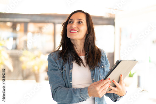 Free Download Middle aged woman holding a tablet with happy expression - GFXLoad