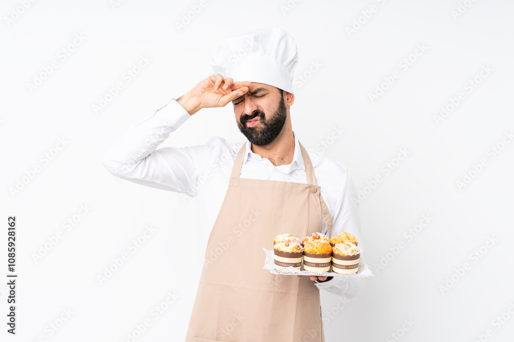 Young man holding muffin cake over isolated white background with tired and sick expression Young man holding muffin cake over isolated white background with tired and sick expression