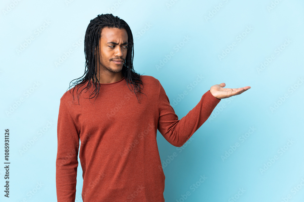 Delivery African American man with braids isolated on white background holding copyspace with doubts Delivery African American man with braids isolated on white background holding copyspace with doubts
