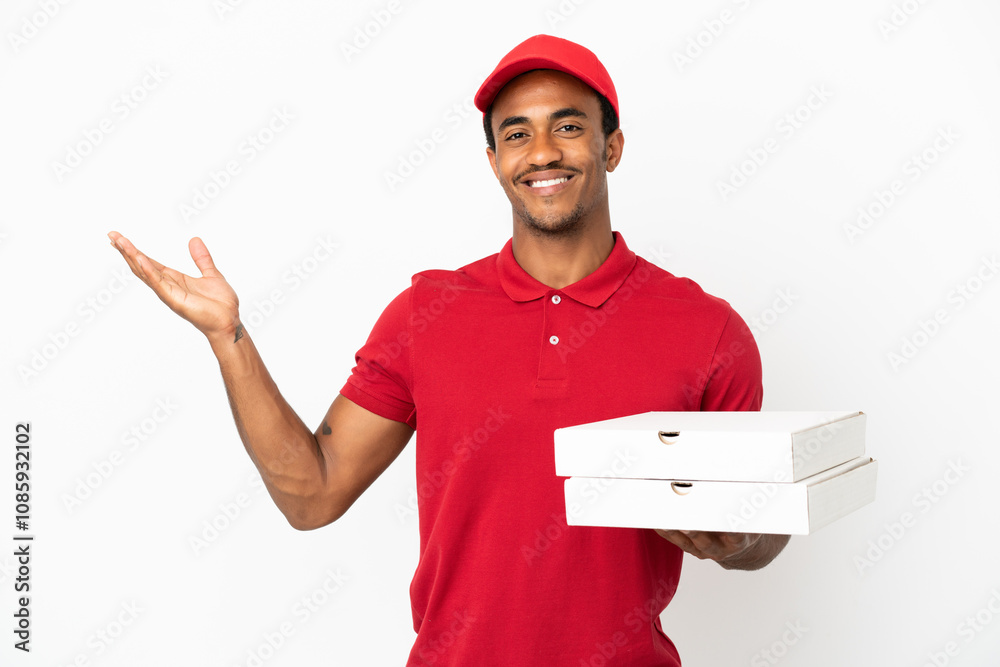 African American pizza delivery man picking up pizza boxes over isolated white wall extending hands to the side for inviting to come African American pizza delivery man picking up pizza boxes over isolated white wall extending hands to the side for inviting to come