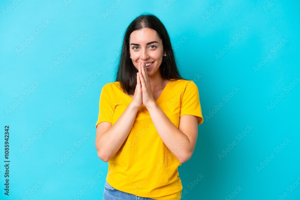 Young caucasian woman isolated on blue background keeps palm together. Person asks for something Young caucasian woman isolated on blue background keeps palm together. Person asks for something