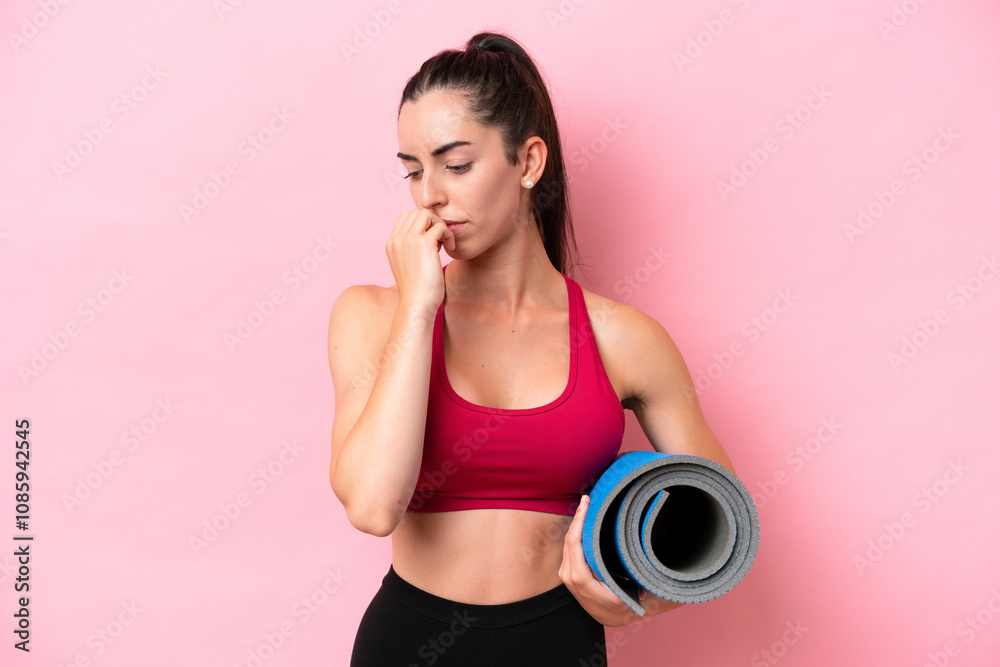 Young sport caucasian woman going to yoga classes while holding a mat isolated on pink background having doubts Young sport caucasian woman going to yoga classes while holding a mat isolated on pink background having doubts