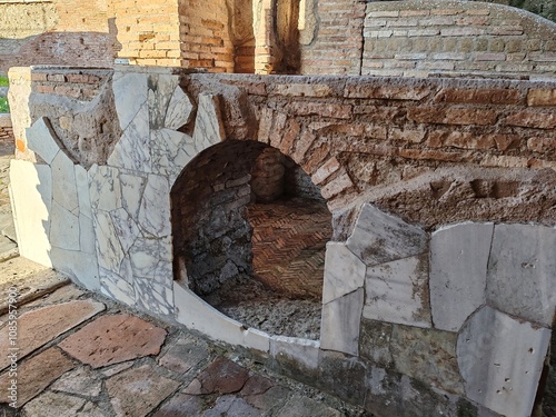 Ostia Antica, Rome, Italy - November 3, 2024. Remains of a Roman Empire room with a marble-lined brick bench, in the Ostia Antica Archaeological Park.