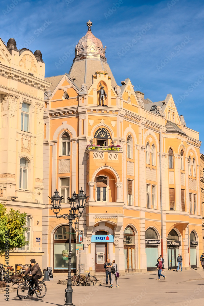 Naklejka premium A panoramic city view of Novi Sad with its iconic bridge over the Danube River is a breathtaking sight. From this vantage point, the city sprawls beneath the sky, with the elegant Varadin Bridge