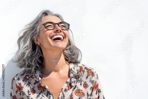 A happy woman with grey hair and glasses smiling widely, isolated on a white background
