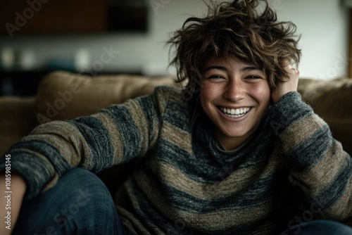 Smiling young caucasian female with short brown hair in cozy sweater on couch