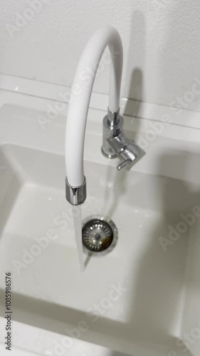 Water Flowing from Faucet into White Kitchen Sink photo